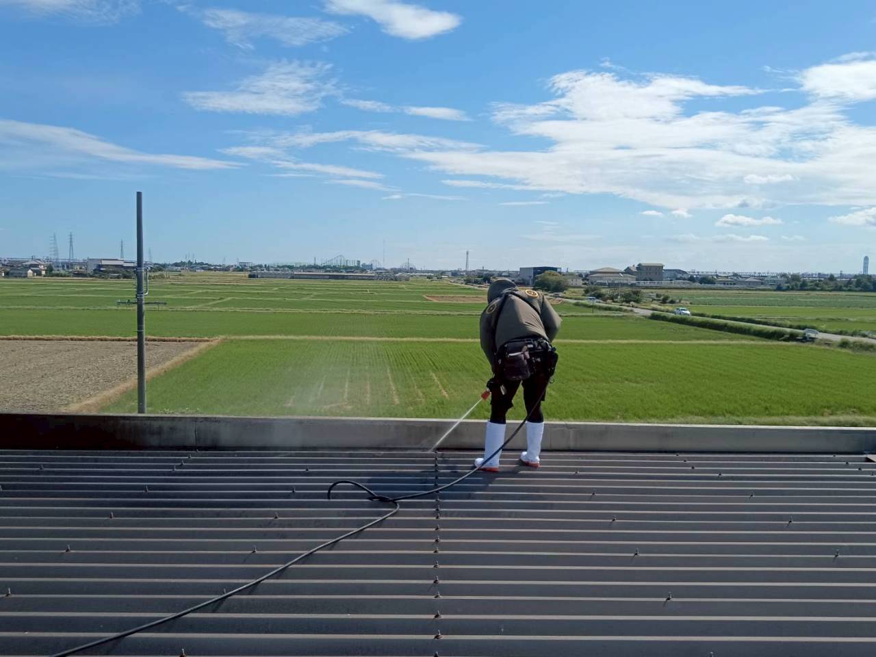 高圧洗浄で屋根表面の汚れを落とすスタッフ